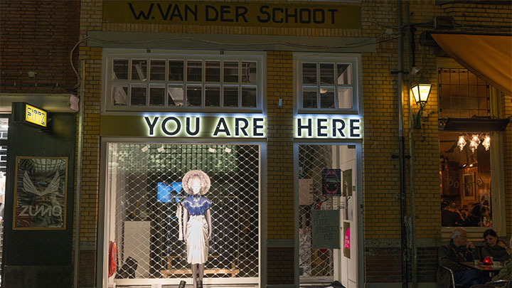 Erhelltes Schaufenster des Modefachgeschäfts 'You are here'