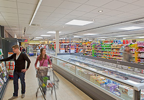 Kunden in den Gängen eines Supermarkts, der mit der energiesparenden Beleuchtung von Philips beleuchtet wird 