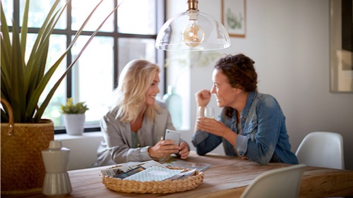 Zwei Frauen zu Hause reden unter einer Philips Lampe