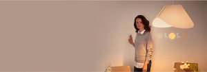 "Frau, die einen intelligenten Dimmschalter einstellt, steuert die warme LED Beleuchtung in einem modernen Wohnraum mit minimalistischem Dekor"
