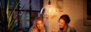 „LED-Filamentlampe-Pendelleuchte im Vintage-Stil, die zwei Frauen bei einem abendlichen Gespräch beleuchtet und ein warmes Ambiente in einer städtischen Wohnung schafft.“