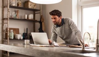 Mann mit Laptop in einem gut beleuchteten Licht im Haus mit LED-Arbeitsplatzbeleuchtung für effiziente Fernarbeit.