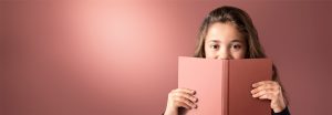 „Ein junges Mädchen, das über ein rosafarbenes Buch blickt, vor einem sanft beleuchteten LED-Hintergrund, der eine warme, gleichmäßige Beleuchtung für eine angenehme Leseumgebung bietet.“
