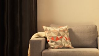 „Gemütliches Wohnzimmer mit moderner LED-Tischleuchte, die den grauen Sessel beleuchtet und ein gemütliches Licht im Haus schafft.“